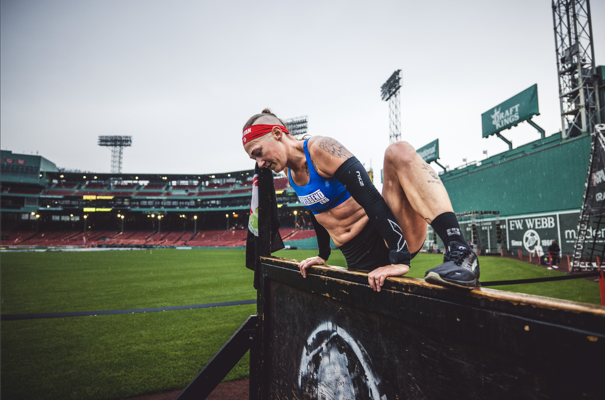 a spartan racer completing a 4 foot over wall obstacle at a stadion race