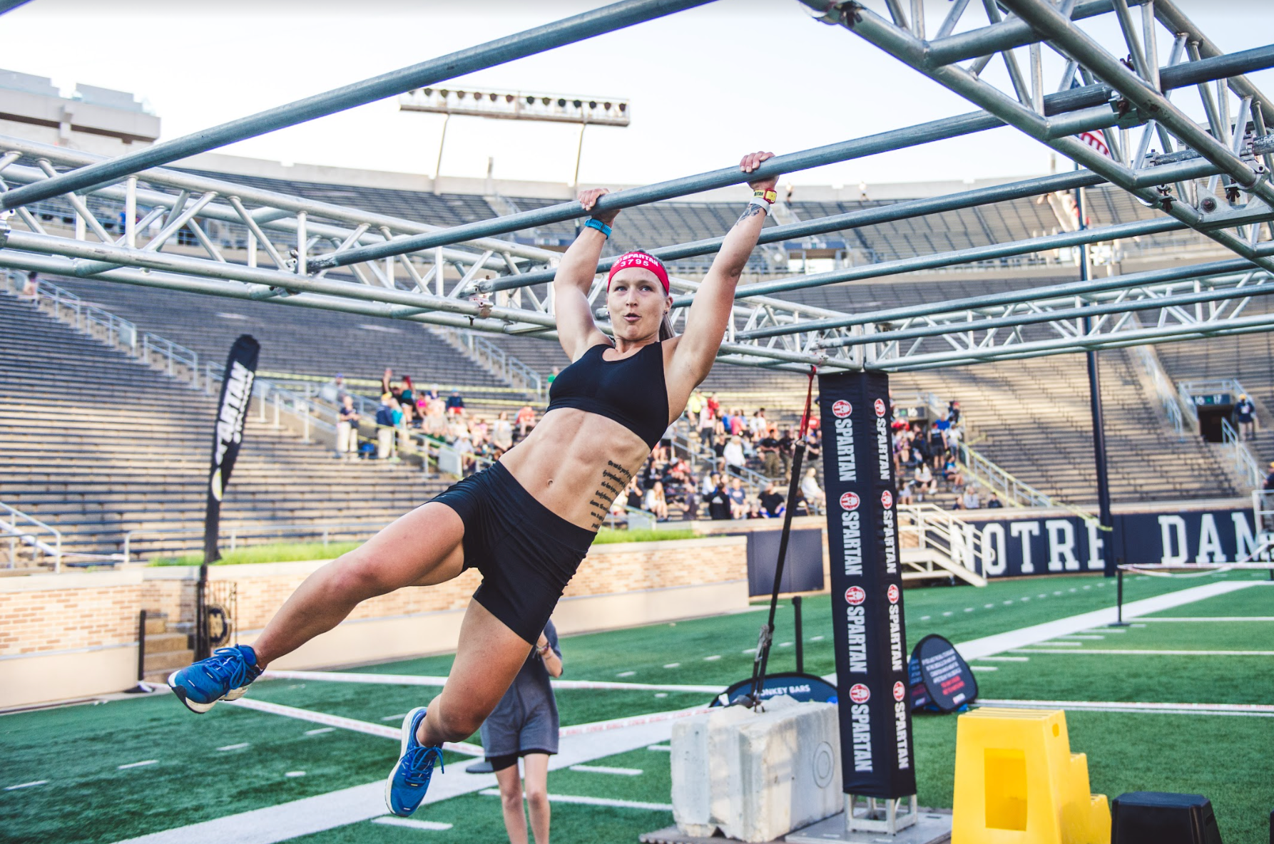 a spartan racer completing the monkey bars obstacle at a stadion race